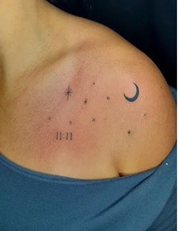 Luna y estrellas en línea fina sobre el hombro, con la hora 11:11
