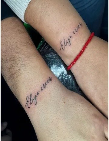 Frase 'Elijo crecer' tatuada en pulseras a juego en dos muñecas